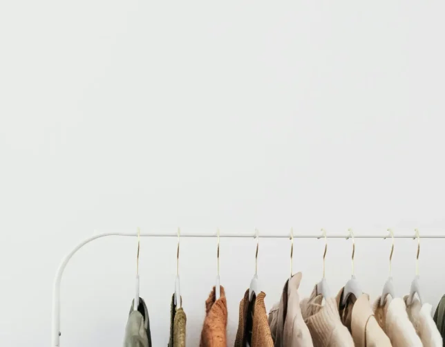 Elegant neutral-toned clothes hanging on a white rail against a plain background, perfect for fashion themes.